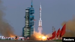 FILE - A rocket loaded with a Shenzhou-9 manned spacecraft lifts off from its launch pad at the Jiuquan Satellite Launch Center, Gansu province June 16, 2012.