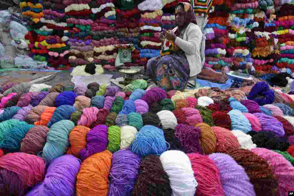 Seorang perempuan merajut saat berjualan benang wol di Ahmadabad, India.