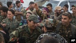 Miembros de las Fuerzas Democráticas Sirias, que respalda Estados Unidos, bailan la tradicional danza siria "dabka" mientras celebran la liberación de Raqqa frente al estadio que fue el último bastión de ISIS en la ciudad. Oct. 20, 2017.