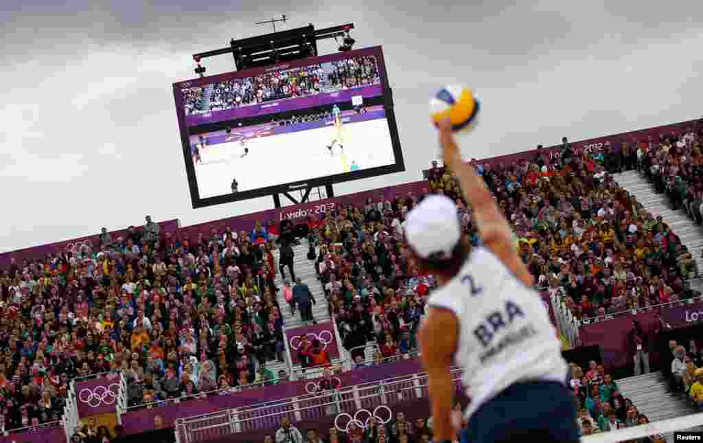 Brazil's Emanuel serves against Poland's Mariusz Prudel and Grzegorz Fijalek during their men's quarterfinals beach volleyball match.