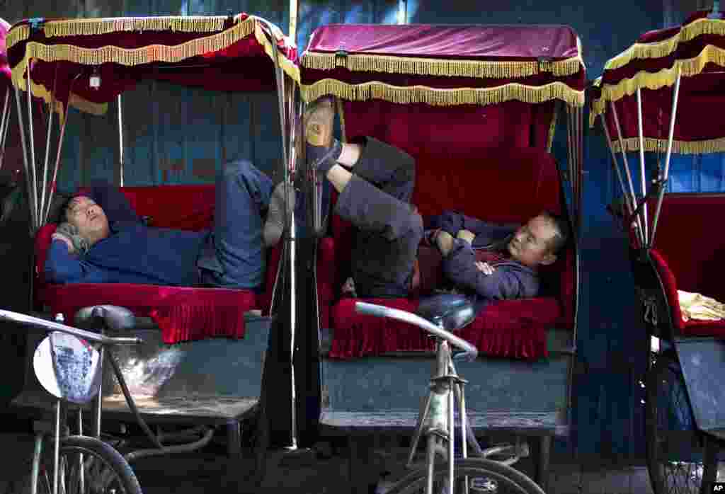 Para penarik becak China (yang disebut tri-shaw) istirahat tidur siang sambil menunggu penumpang di sebuah pusat wisata di Beijing.