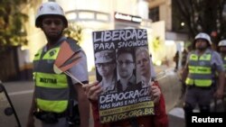Un estudiante de Sao Paulo muestra un cartel con fotos de Manning, Snowden y Assange que pide democracia en las calles y en las redes sociales.