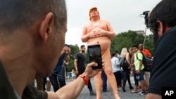 FILE - People take photos of a statue of a naked Republican presidential nominee Donald Trump in New York's Union Square, Aug. 18, 2016. City parks workers later removed the statue.