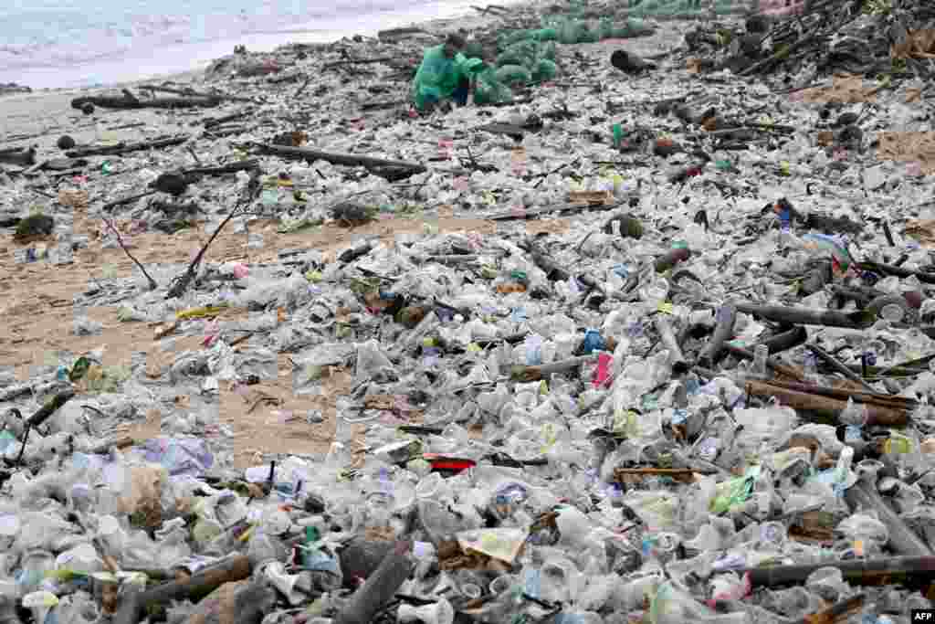 A man collects plastic and other debris washed ashore at a beach in Kedonganan, Badung Regency, on Indonesia's resort island of Bali.