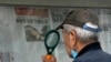 A man uses a magnifying glass to read a newspaper headline reporting on Chinese People's Liberation Army (PLA) conducting military exercises, at a stand in Beijing, Aug. 7, 2022. 