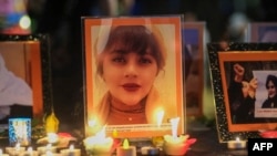 FILE - Candles and pictures of Mahsa Amini are shown during a vigil for Mahsa Amini, who died in custody of Iran's morality police, in Los Angeles, Sept. 29, 2022. 