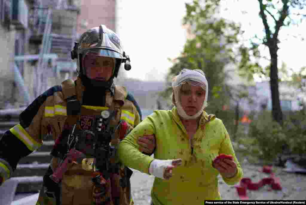 A rescuer helps an injured woman at a site of a building damaged by a Russian missile strike in Kyiv, Ukraine. At least 11 people were killed and 64 wounded in Russian missile strikes across Ukraine, the state emergency service said.