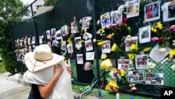 People embrace at a makeshift memorial for people dead or missing after the collapse of a condominium, in Surfside, Fla., June 28, 2021.