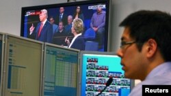 A trader works at his desk as the U.S. presidential town hall debate between Republican U.S. presidential nominee Donald Trump and Democratic nominee Hillary Clinton is shown on TV, at Citibank's trading floor in Sydney, Australia, Oct. 10, 2016.