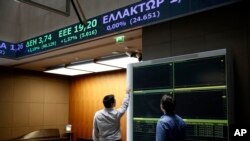 Two men check an index board at the reception hall of the Athens' Stock Exchange, in Athens, Aug. 4, 2015.