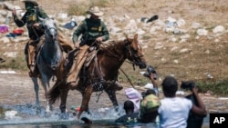 Agenti carinske službe na konjima usmjeravaju migrante koji prelaze rijeku Rio Grande iz Meksika u Texas, 19. septembra 2021.