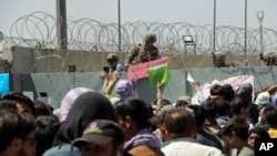 FILE - U.S. soldier holds a "Gate Closed" sign as hundreds of people gather near an evacuation checkpoint on the perimeter of Hamid Karzai International Airport, in Kabul, Afghanistan, Aug. 26, 2021. 