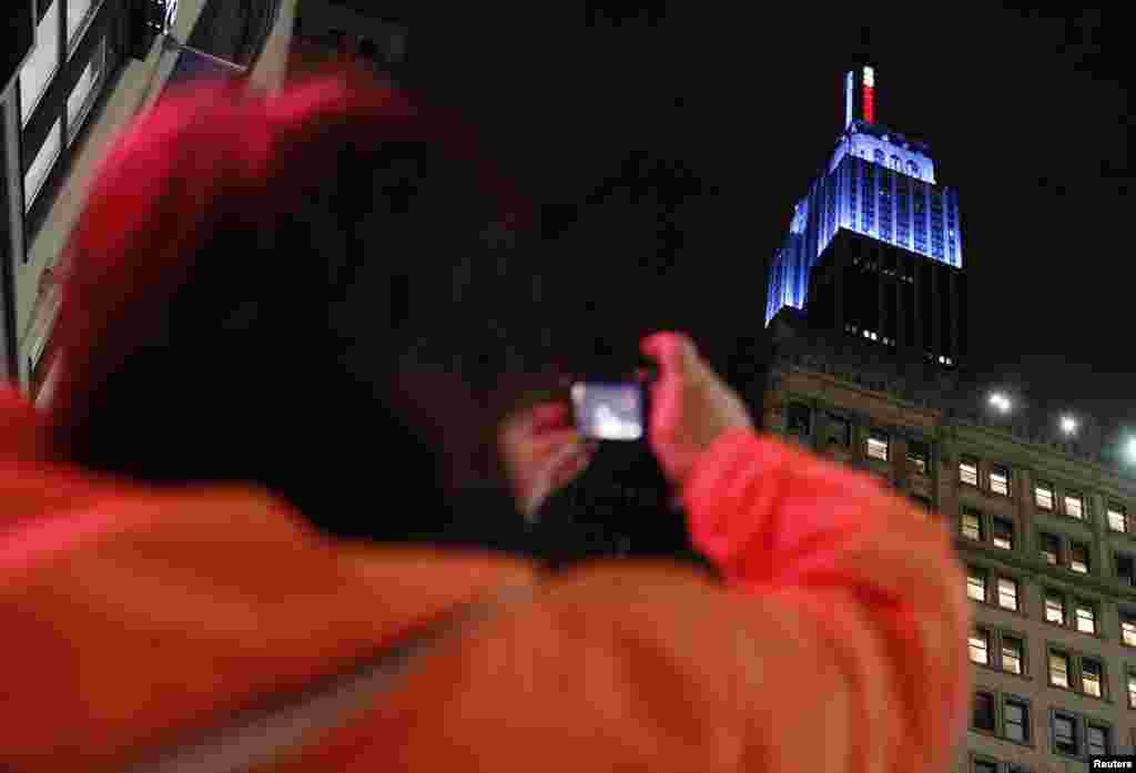 Bir qadın prezident Barak Obamanın qələbəsi münasibətilə Demokratların rəngi sayılan göy rəngdə işıqlandırılmış Empire State binasının şəklini çəkir. 7 noyabr, 2012.