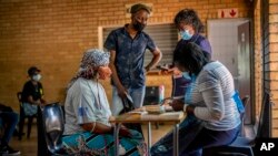 FILE - People are processed before receiving their COVID-19 vaccinations at the Orange Farm, South Africa, multipurpose center, Dec. 3, 2021.