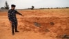 Mwanajeshi wa jeshi la utawala wa Libya unaotambulika kimataifa akionyesha makaburi ya pamoja yaliogunduliwa Tarhouna , Libya, Juni 11, 2020.