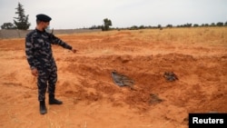 Mwanajeshi wa jeshi la utawala wa Libya unaotambulika kimataifa akionyesha makaburi ya pamoja yaliogunduliwa Tarhouna , Libya, Juni 11, 2020.