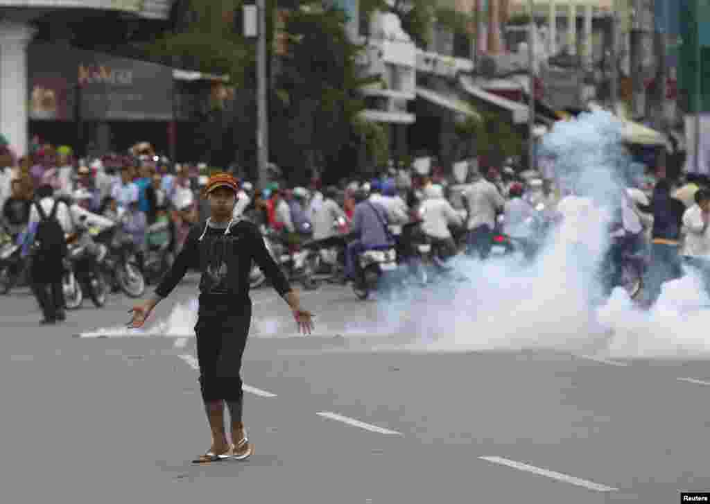 A protester supporting the opposition Cambodia National Rescue Party reacts as police fire tear gas during clashes near the Royal Palace in Phnom Penh. Sept. 15, 2013.