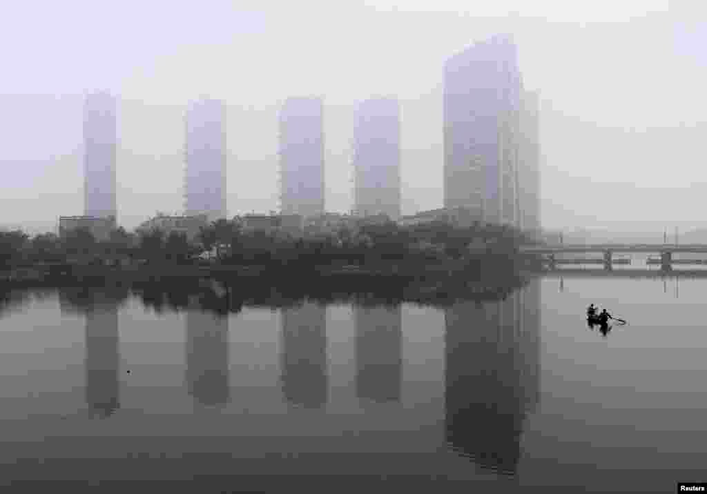 A man rows a boat on a river during a hazy morning in Shaoxing, Zhejiang province, June 16, 2013. 