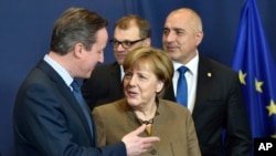 British Prime Minister David Cameron speaks with German Chancellor Angela Merkel during a photo session at a European Union summit in Brussels, Feb. 18, 2016.