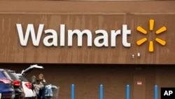 FILE - Caption A shopper loads her car after shopping at a Walmart in Pittsburgh, Feb. 22, 2018.