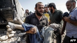 A Syrian carries the body of a child at the site of a reported regime airstrike on the village of Deir Sharqi on the eastern outskirts of Maaret al-Numan in Syria's northern province of Idlib, Aug. 17, 2019.