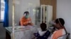 Seorang tenaga kesehatan berbicara dengan seorang pasien dari balik pelindung plastik untuk mencegah penularan virus corona di sebuah puskesmas di Yalimo, Provinsi Papua, 21 April 2020. (Foto: AP)