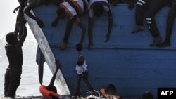 FILE - Migrants try to pull a child out of the water as they wait to be rescued in the Mediterranean sea, north of Libya, Oct. 4, 2016.
