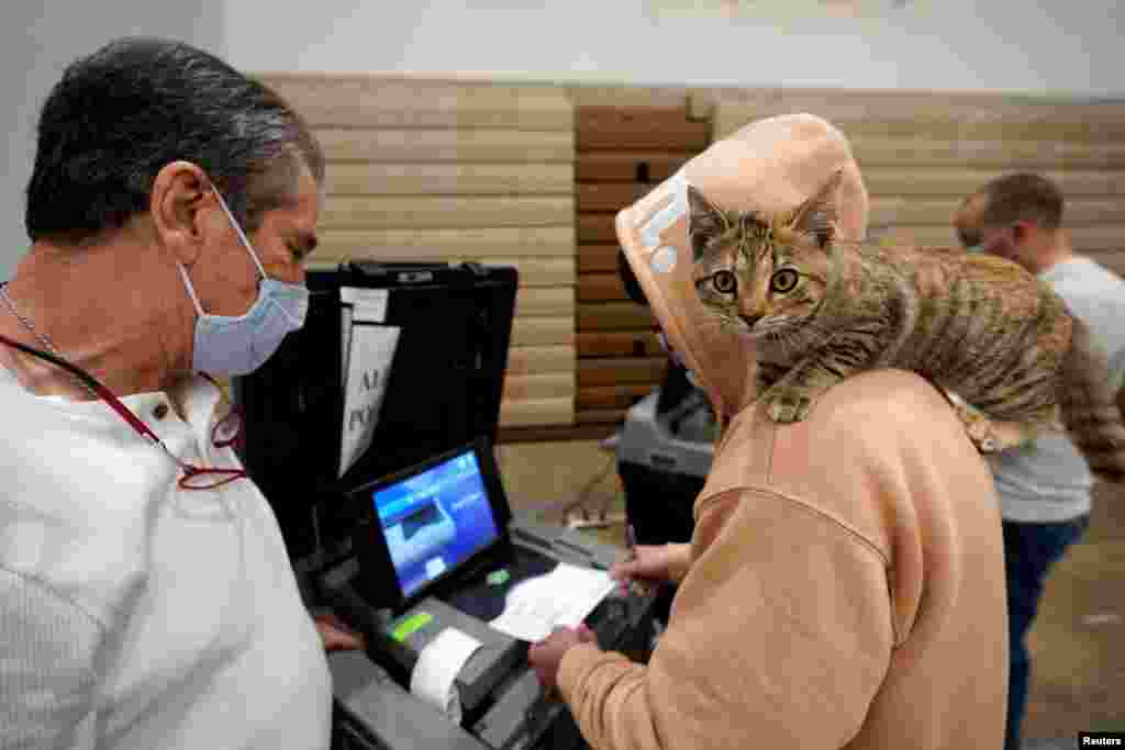 Barton Foley, de 32 años, con su gato en el hombro, emite su voto el día de las elecciones en Ballard High School en Louisville, Kentucky, el 3 de noviembre de 2020.