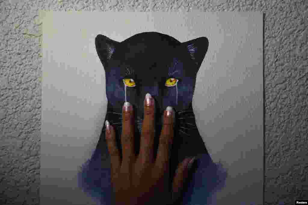 A woman touches a drawing of a crying black panther, during a protest against Premchai Karnasuta, President of Thailand’s largest construction company Italian-Thai Development (ITD) PCL, before a supreme court verdict on his poaching case, in Bangkok, Thailand, Dec. 7, 2021.