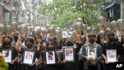 معترضان به کودتا در تظاهراتی علیه نظامیان، تصاویر کشته‌شدگان را در دست گرفته‌اند؛ یانگون، ۱۶ فروردین ۱۴۰۰