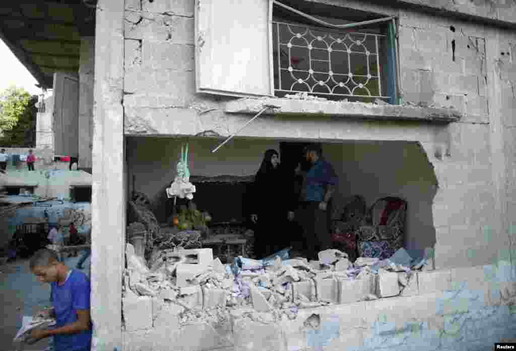 Palestinians stand inside a house which witnesses said was damaged by an Israeli air strike in Jabaliya refugee camp in the northern Gaza Strip, August 4, 2014.