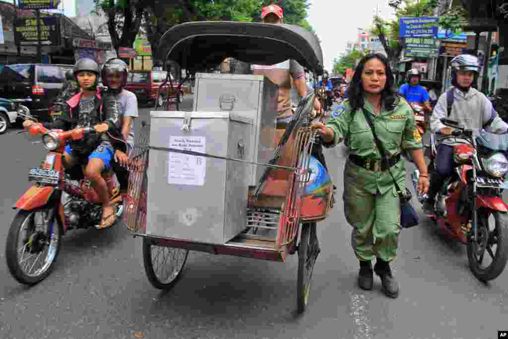 Seorang petugas keamanan mengawal becak yang membawa kotak-kotak berisi kertas suara di Yogyakarta (8/7). (AP/Slamet Riyadi)