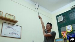 FILE - In this March 19, 2020, photo, a PE teacher demonstrates a badminton technique to his students during an online class at Nguyen Tat Thanh school in Hanoi, Vietnam.