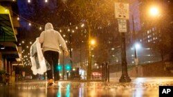 A person carries his dry cleaning while walking in the rain through midtown Atlanta, Wednesday, Dec. 23, 2015. 