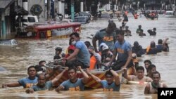 Rescuers pull a rubber boat carrying residents through a flooded street after Typhoon Vamco hit in Marikina City, suburban Manila on November 12, 2020. (Photo by Ted ALJIBE / AFP)