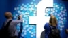 FILE - People stick notes on a Facebook logo at a Facebook developer conference, in San Jose, California, April 30, 2019.