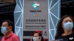 2021年8月18日，幾名帶口罩的民眾走過一個2022年北京冬奧會倒計時看板。