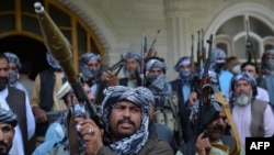 FILE - Afghan militia members gather with their weapons to support Afghanistan security forces against the Taliban, at Afghan warlord and former mujahedeen leader Mohammed Ismail Khan's home, in Herat, Afghanistan, July 9, 2021. 