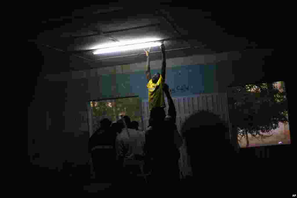 A boy changes a light fixture at a polling station during Mali's parliamentary elections in Gao, Nov. 24, 2013.