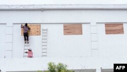 Workers board up the windows of a store in preparation for Hurricane Nana, expected as a Category 1 hurricane with winds up to 152 kph, in Belize City, Belize, on Sept. 2, 2020. 