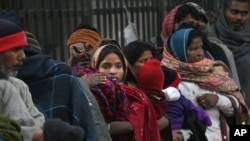 FILE - Indian homeless people wait for free food outside a temple, in New Delhi, India, Jan. 1, 2013.