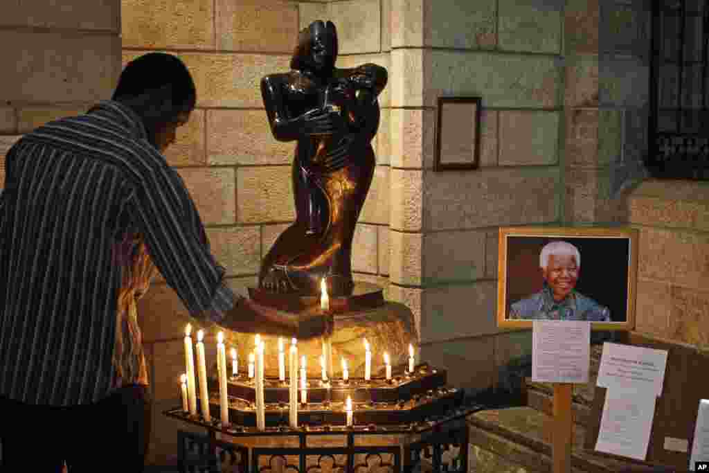 A man places a candle inside the St. George’s Cathedral in Cape Town, South Africa, July 17, 2013.
