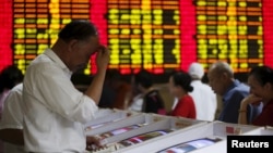 Investors look at computer screens showing stock information at a brokerage house in Shanghai, China, July 8, 2015.