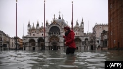 Seorang wanita melintasi alun-alun St. Mark yang dibanjiri oleh Basilika Santo Markus setelah ketinggian air pasang semalam "Alta Acqua", awal 13 November 2019 di Venesia. (Foto: AFP)