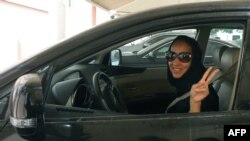 FILE - Saudi activist Manal al-Sharif flashes the sign for victory as she drives her car in Dubai, Oct. 22, 2013.