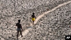 ARCHIVES - Un homme et un garçon traversent le lit asséché de la rivière Yamuna à New Delhi, en Inde, le lundi 2 mai 2022.