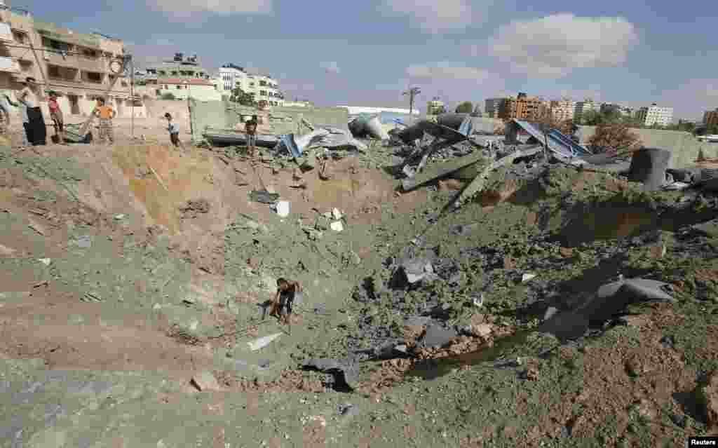 A Palestinian inspects a crater police said was caused by an Israeli air strike in Gaza City, July 3, 2014.