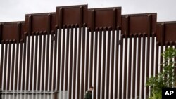 A border patrol agent walks along a border wall separating Tijuana, Mexico, from San Diego, Wednesday, March 18, 2020, in San Diego. (AP Photo/Gregory Bull)