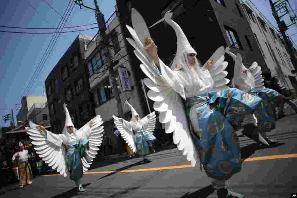 Para penari dengan menggunakan kerudung ala burung Heron menari sambil berparade di jalan-jalan menuju Kuil Asakusa di kompleks Kuil Sensoji di Tokyo, Jepan, sebelum Festival Tahunan Sanja, salah satu dari tiga festival penting yang dijadwalkan pada 16-18 Mei.