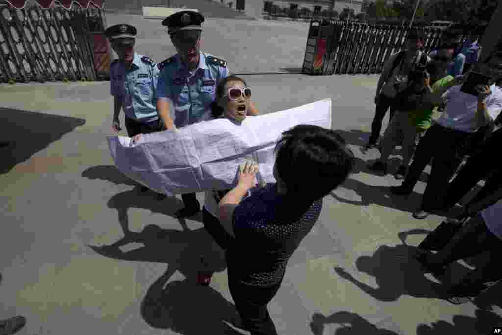 2013年8月21日,一名中国妇女(中戴墨镜者)在济南中级人民法院外抗议。除了少数薄熙来支持者到场抗议外,还有个别公民利用薄案开审引起媒体关注的机会申诉自己的冤情。